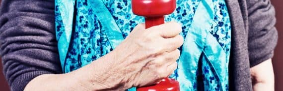 older woman holding red weight (muscle strength concept)