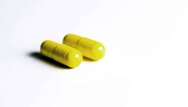 two yellow pills on white