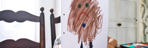 child behind drawing of brown sad blurry person