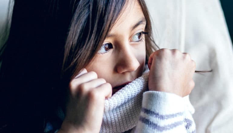 girl hiding mouth in turtleneck sweater - tics