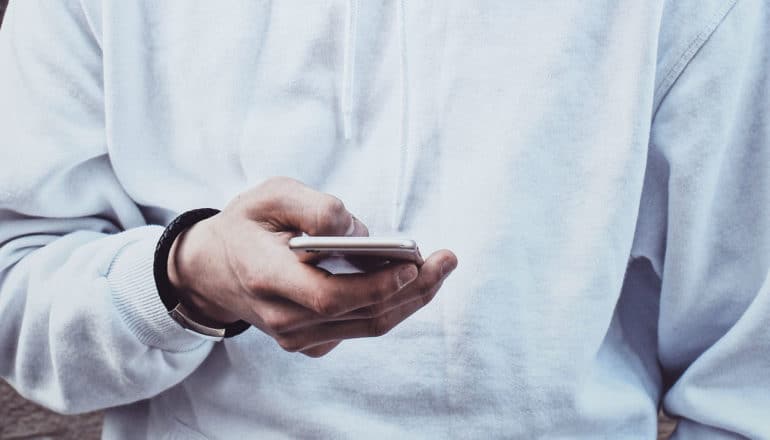 hand holds phone against white sweatshirt