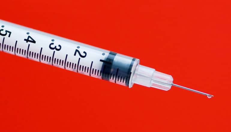 HPV vaccine - syringe on red