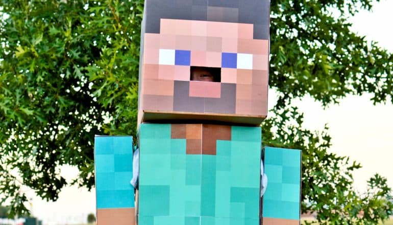 person peeks out of cardboard Minecraft costume