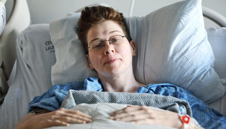 person in hospital bed looking groggy - LGB women after cancer concept