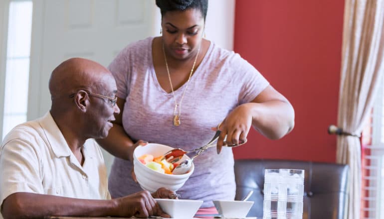 woman serves seated man fruit salad