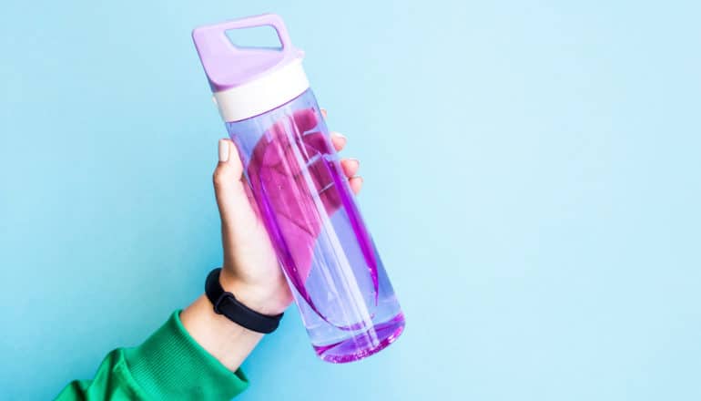 hand holds up purple water bottle - photoacoustic effect device