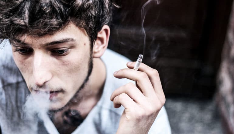 man sitting and smoking (e-cigarette ban concept)