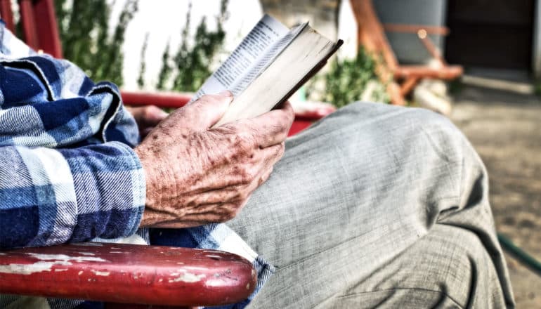 older man reading book (Alzheimer's disease concept)