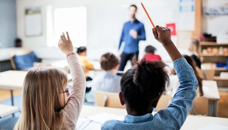 two girls raising hands in class - punishment