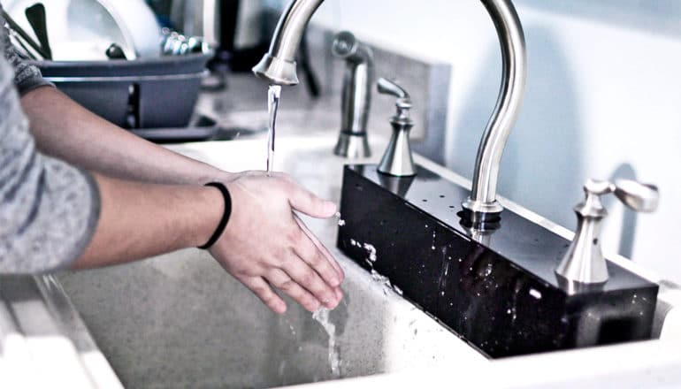 A person washes their hands in the fake autonomous sink