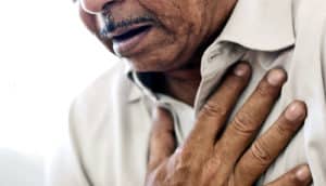 a man holds his hand over his chest as he struggles to breathe.