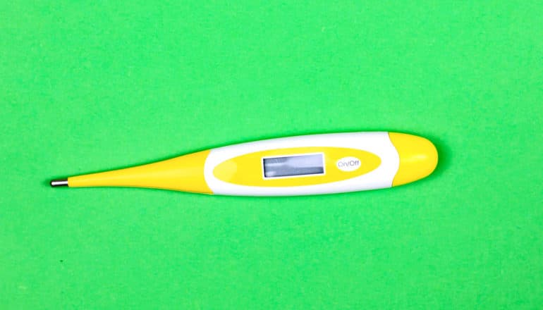 yellow thermometer on green background