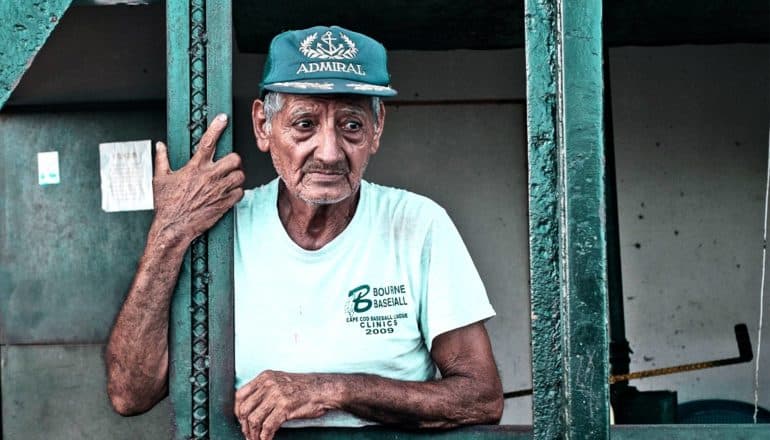 The image shows an older man looking concerned, lost in thought while he holds onto a metal rail. (memory concept)