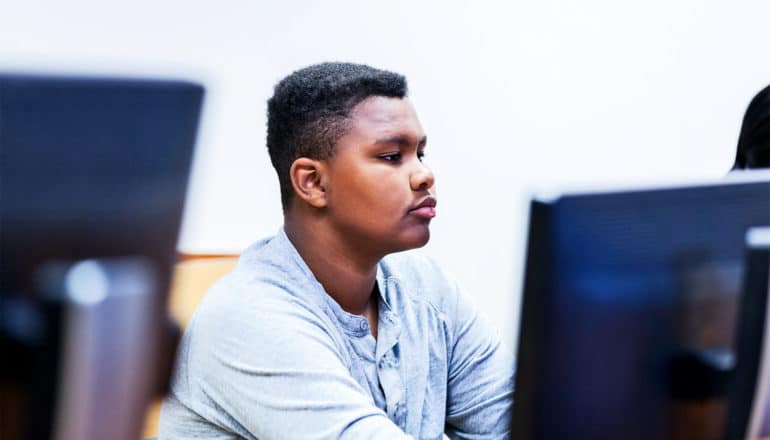 Young black teen in a computer lab wearing a gray shirt