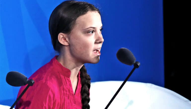 Greta Thunberg delivers a speech on climate change action against a blue background at the United Nations General Assembly