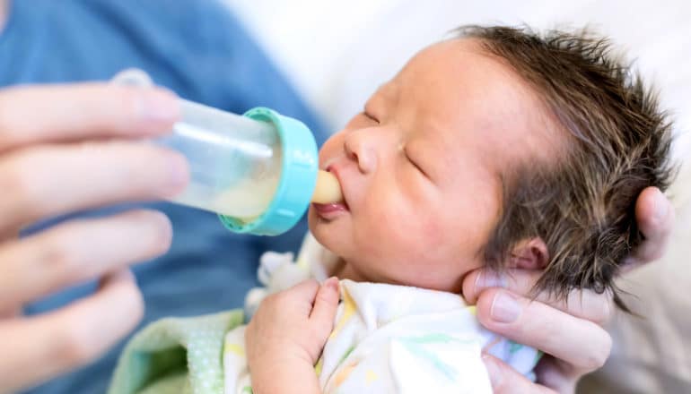 newborn baby drinks from bottle