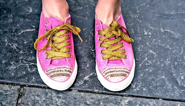 feet in hot pink sneakers with gold laces