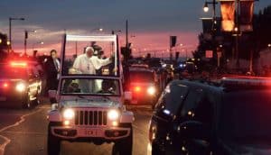 pope francis stands in glass-topped vehicle, waves to unseen crowd