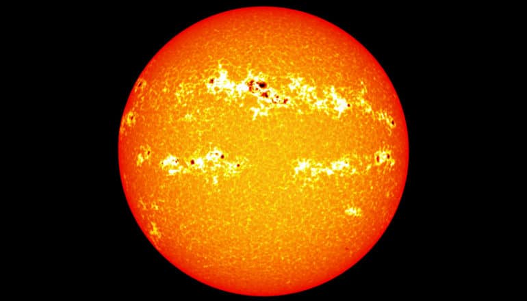 The sun appears against a black background with several visible sunspots near its center