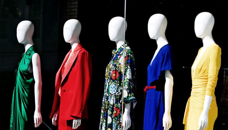 Mannequins wear different colorful dresses against a dark background