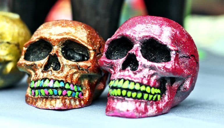 Two colorful skulls sit on a table