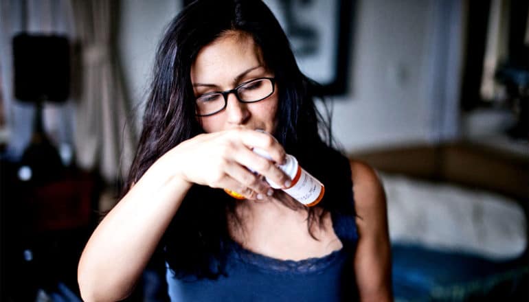 A woman looks at a couple pill bottles