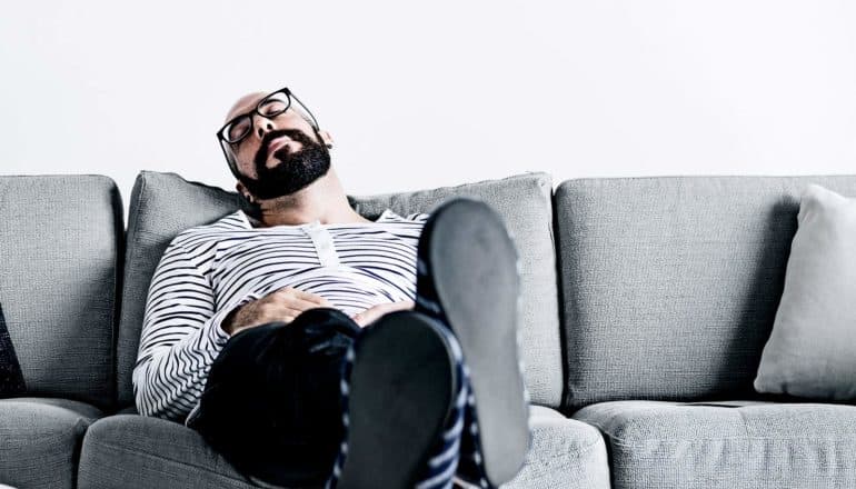 man sleeps on couch with feet up