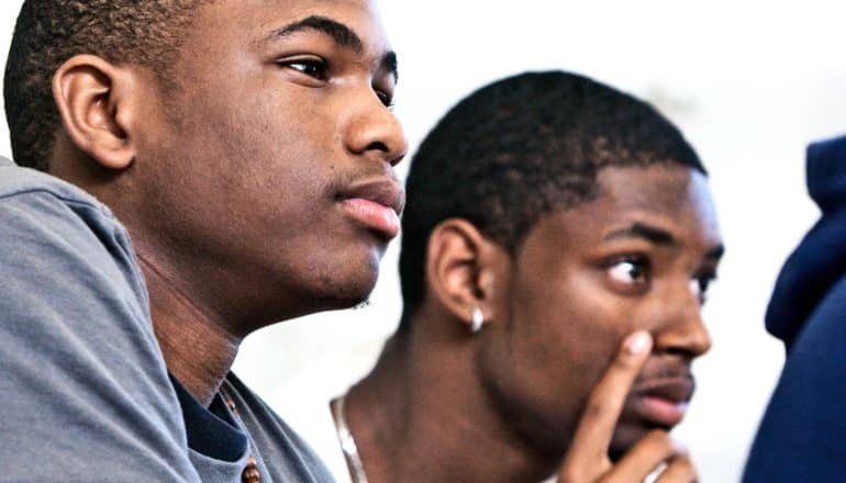 Two students sit and listen in class