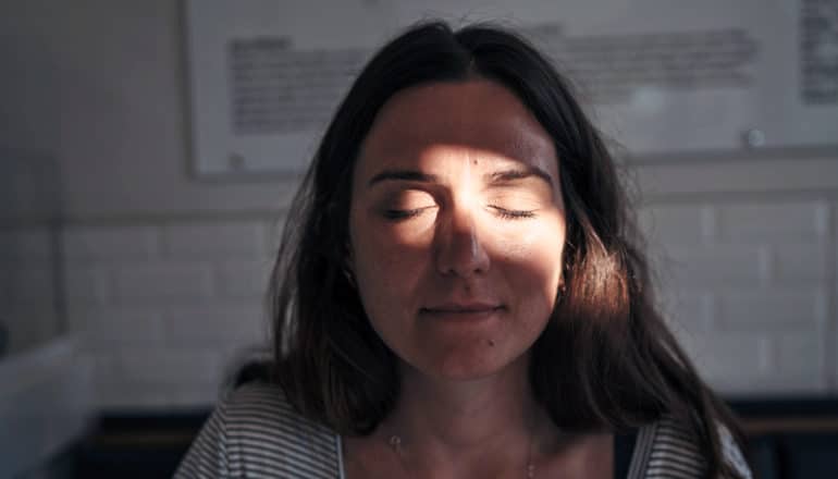 light shines on person's face, eyes closed