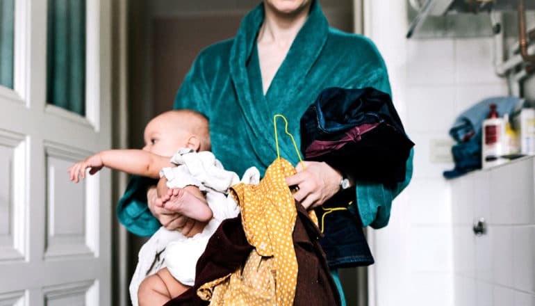 person in bathrobe holds baby, clothing, clothes hanger