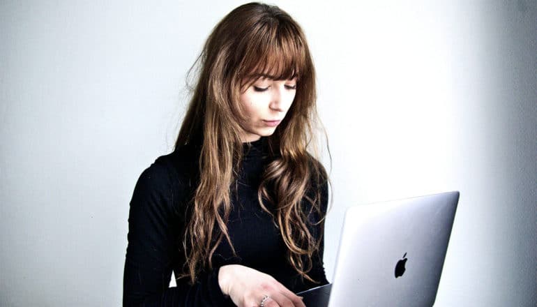 A woman uses her laptop against a gray background