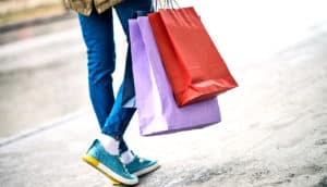 A person walks with colorful shopping bags on concrete