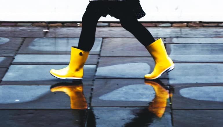 legs of person striding in yellow rain boots