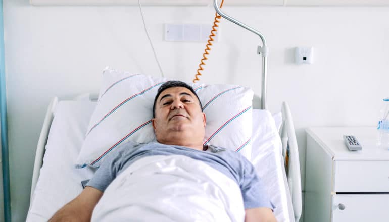 A patient lays in a hospital bed in a white room