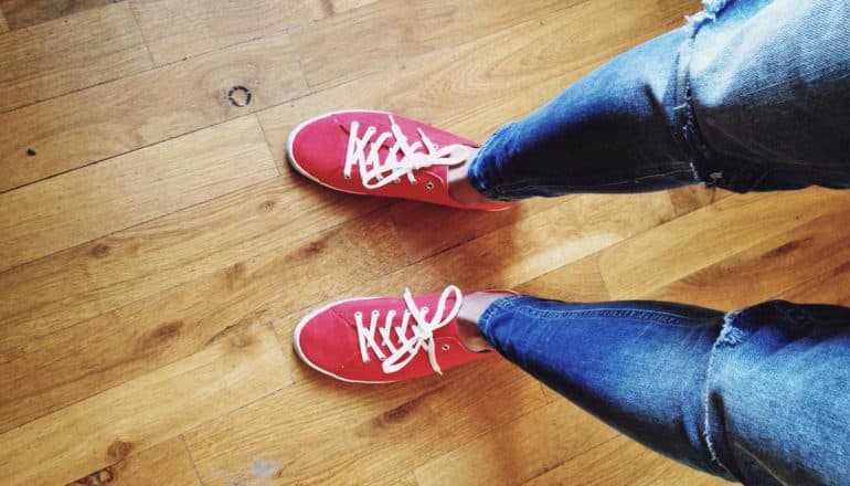 looking down at legs in jeans and feet in red sneakers