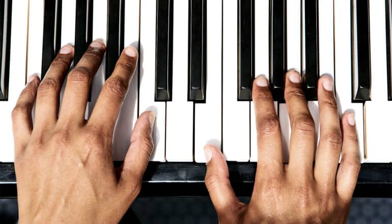 Two hands sit on piano keys