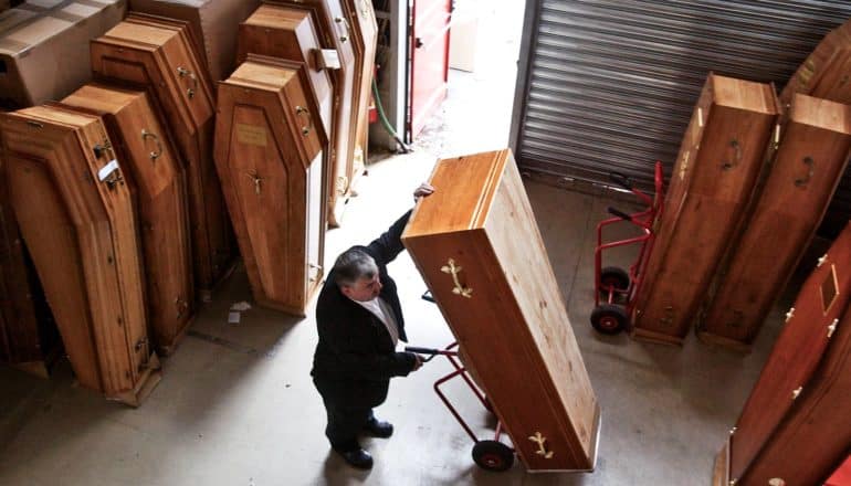 person moves a coffin in warehouse