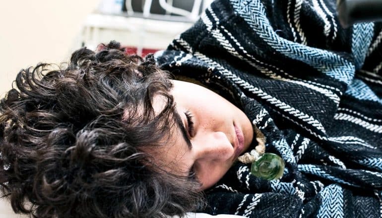 A boy lays in a hospital bed on his side