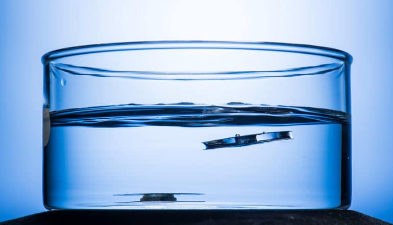 two metal objects in water, one is moving toward the surface