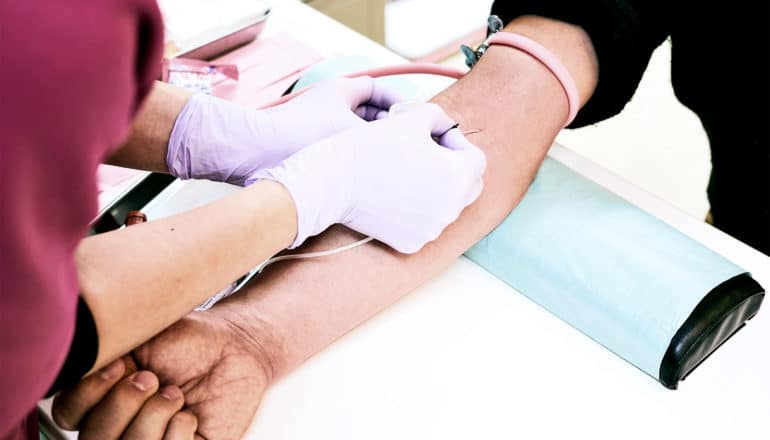 A health care worker draws blood from a person's arm