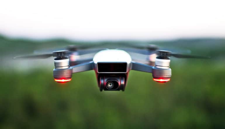 quadcopter drone with red lights over blurry green background