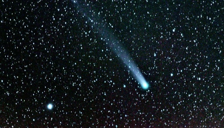 A comet streaks across a black, starry sky