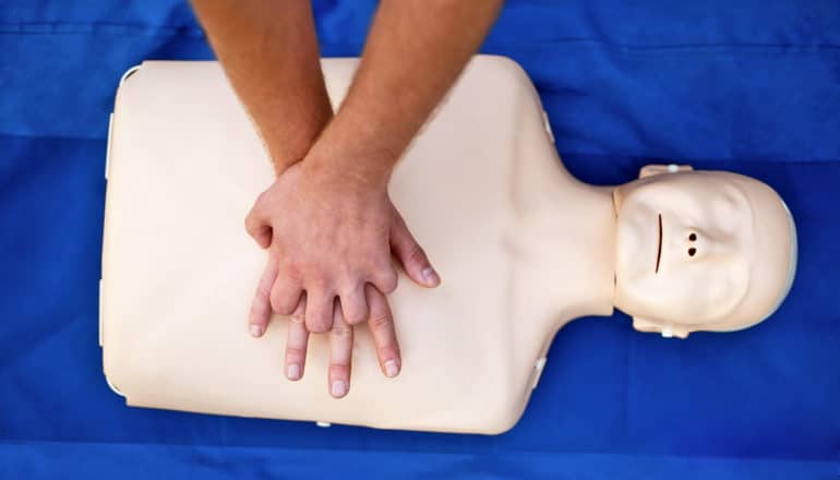 hands press on chest of CPR training dummy