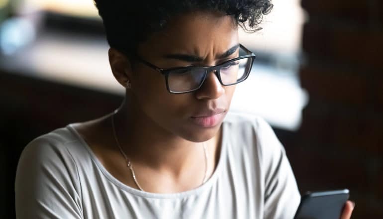 person looks at phone with concerned expression