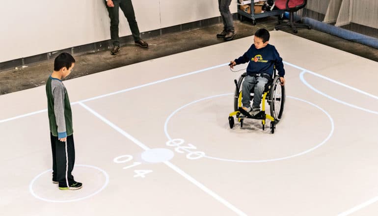 Darren stands in his circle while his brother Bryan sits in a wheelchair in his own circle across the court, which is divided in half with goals on either side