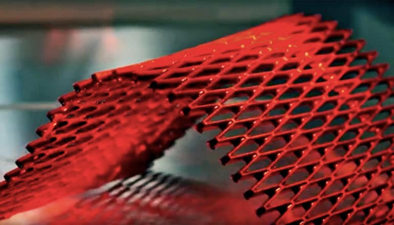 The smart material is bending under a heat lamp, which makes the lattice-like sheet appear bright red