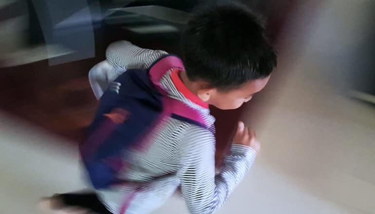 blurry child running with backpack on