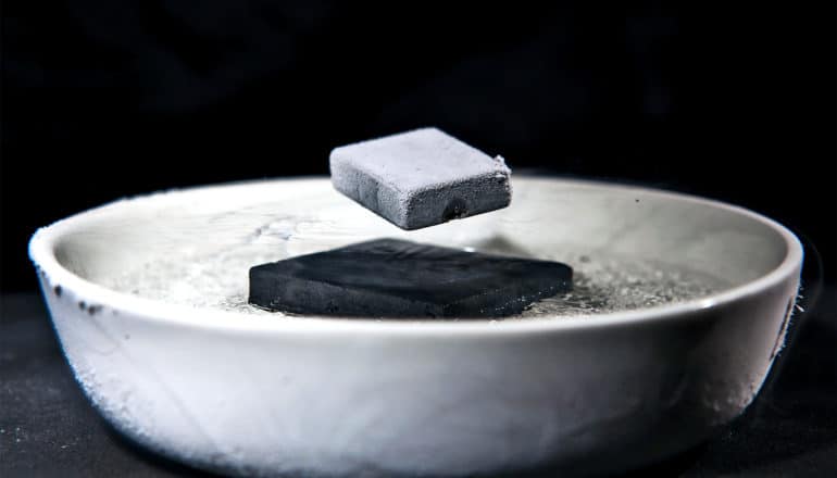 A gray magnet levitates over a black magnet in a bowl