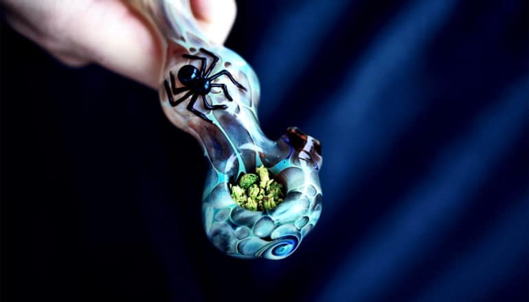 A person holds a blue-ish marijauna pipe