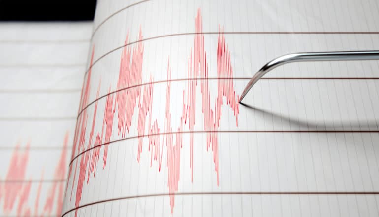 A seismograph charts earthquake activity in red on white paper